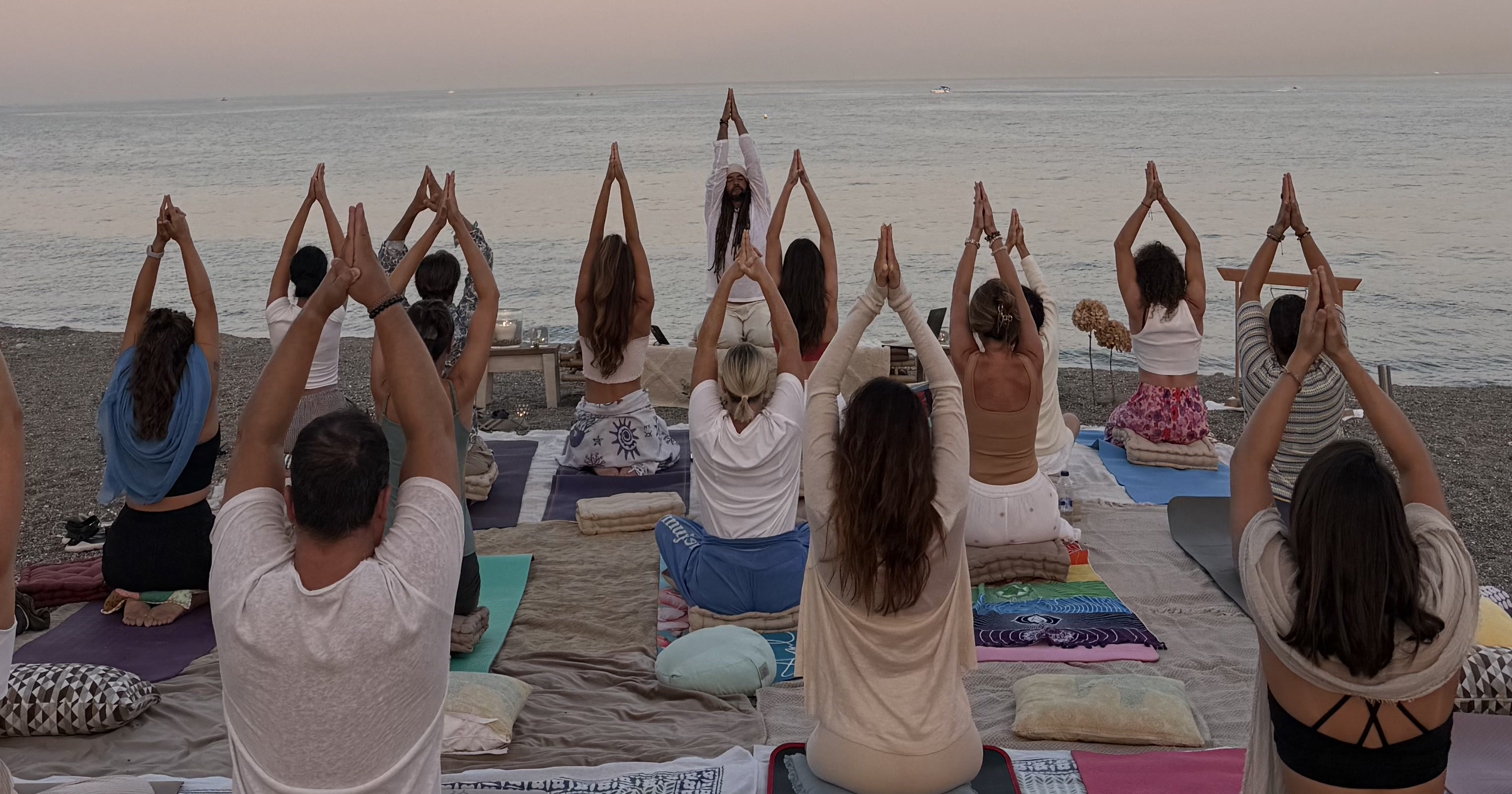 Círculo de yoga al atardecer frente al mar